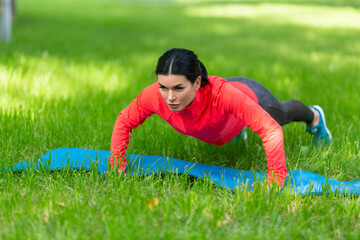 Fototapeta na wymiar Woman doing a push up exercises in city park