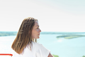 happy middle age free woman enjoying river landscape. brown haired woman wearing white t-shirt. calm and relaxing place. local tourism concept. weekend travelling and staycations. real people