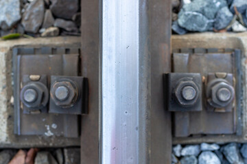 Metal rail close up with background of rusty screws and gravel