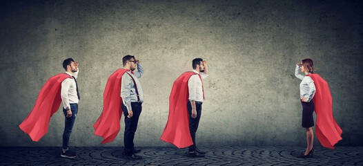 Group of three men and a woman imagining to be a super hero looking at each other