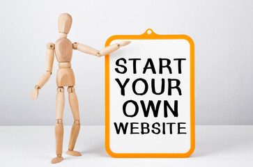 Wooden man shows with a hand to white board with text START YOUR OWN WEBSITE