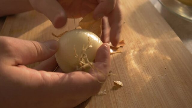 Peeling an Onion for breakfast in beautiful morning light on wooden table.
Zwiebel sch&auml;len zum Fr&uuml;hst&uuml;ck bei Sonnenaufgang auf einem Holztisch.