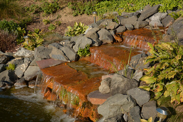 garden water cascades made of red stones as an idyllic harmony background