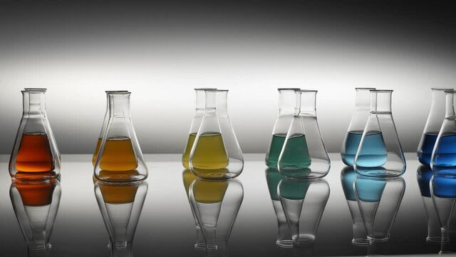 Empty and mixed color liquid filled erlenmeyer flasks reflecting on table