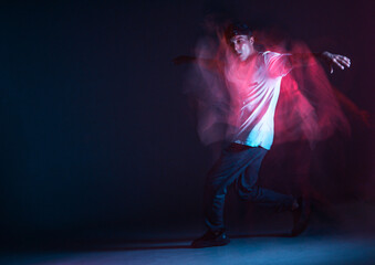 Stylish young guy breakdancer dancing hip-hop in neon light. Dance school poster. Long exposure shot