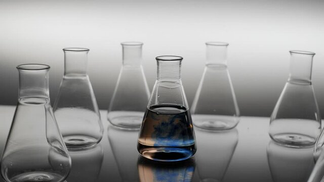 Pouring blue colored drops into erlenmeyer flask