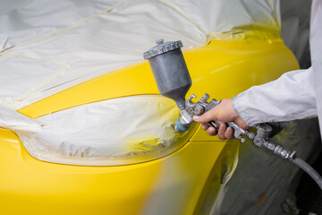 Auto body repair series: Mechanic painting yellow sports car