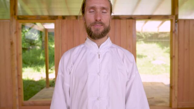 Close-up Bearded caucasian man wearing white clothes to practice concentration and breathing before practicing qigong tai chi