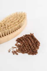 Sample of coffee scrub with a brush for dry massage close-up isolated on a white background. Cosmetology, body care.