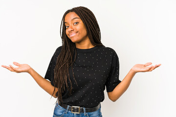 Young african american woman isolated on white background doubting and shrugging shoulders in...