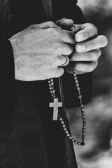 The priest holds a chain with a cross in his hands
