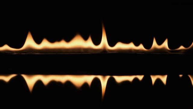 Slow motion, pulsating fire and its reflection on a black background.