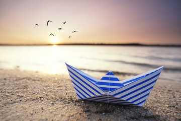 blau weißes Papierboot am Strand