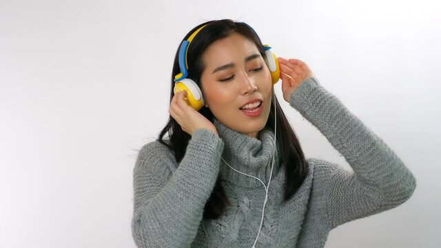 Asian woman listening music, singing song with happiness, smile face. Attractive beautiful young girl love sing a song and listen music that make her happy, relaxed time. white background, copay space