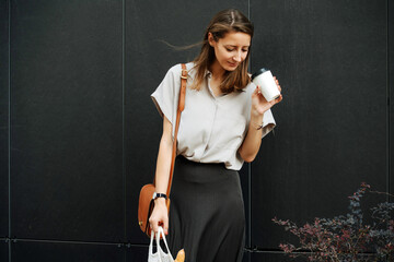 Woman on the street looking inside empty coffee cup