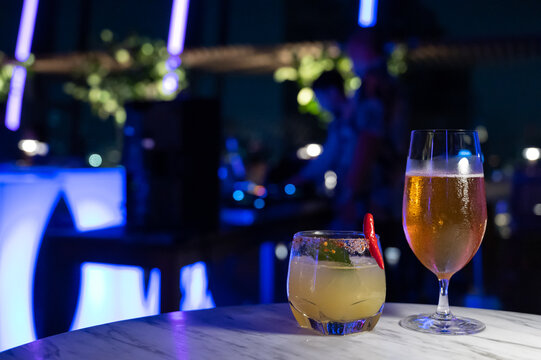 Food and drinks series: Glass of beer and mocktail on marble top table in night club