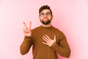 Young caucasian man isolated on pink background taking an oath, putting hand on chest.
