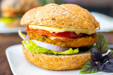 Eating of fresh and healthy vegetarian hamburgers with grilled spinach or pumpkin burgers, organic buns and vegetables