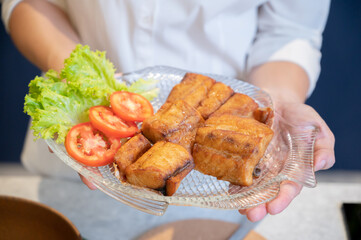 Cooking series: Asian woman offering plate of fried fish