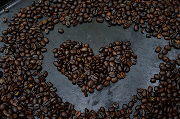 heart of black coffee on black background with roasted coffee beans
