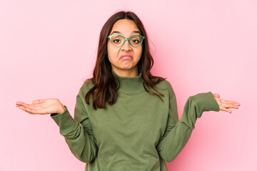Young mixed race hispanic woman isolated doubting and shrugging shoulders in questioning gesture.