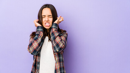 Young mixed race hispanic woman isolated covering ears with fingers, stressed and desperate by a loudly ambient.