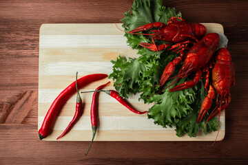 Steamed boiled crawfish on a chopping Board. Crayfish with herbs pepper and tomatoes