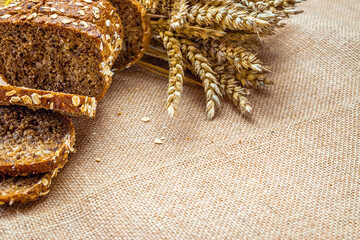 Rye bread isolated. Bakery with crusty loaves and crumbs. Fresh loaf of rustic traditional bread with wheat grain ear or spike plant on natural cotton background. Bio ingredients, healthy with seeds.