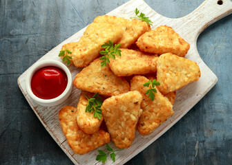 Hash brown potato with ketchup on white wooden board