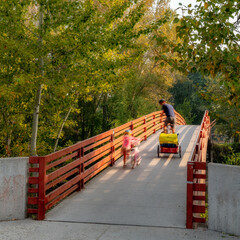 Daddy and daughter ride bikes over the Boise river bridge