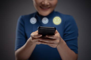 Asian woman using smart phone for voting with emoticon hologram effect.
