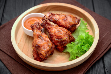 BBQ chicken wings with spicy sauce on a wooden plate