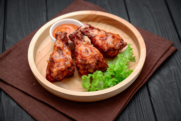 BBQ chicken wings with spicy sauce on a wooden plate