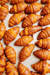 Top view of freshly baked crispy golden croissants cooling on a surface