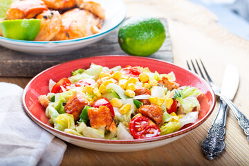 Fresh salad with grilled salmon on table.