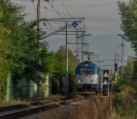 Blue electric engine and expres passenger train near Budweis station in summer