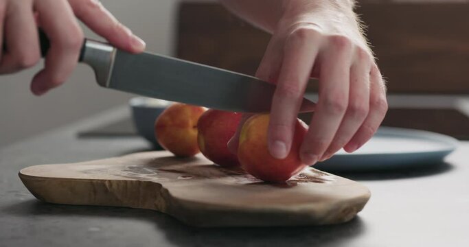Slow motion man cut fresh nectarines on a olive wood board