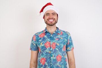 Young caucasian man wearing hawaiian shirt and Santa hat over isolated white background with a happy and cool smile on face. Lucky person.