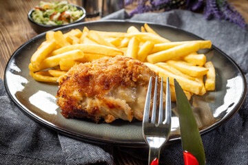 Fried chicken breast stuffed with bacon and cheese served with chips and salad.