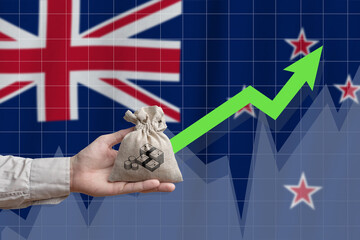 The concept of economic growth in New Zealand. Hand holds a bag with money and an upward arrow