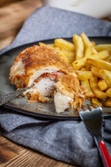 Fried chicken breast stuffed with bacon and cheese served with chips and salad.