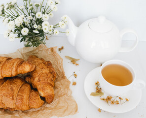 Hot tea made of linden flowers on white table.