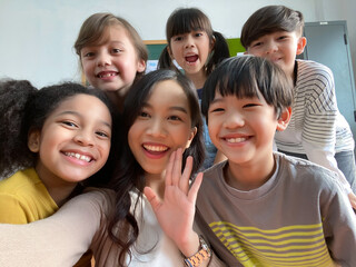 Smiling young Asian teacher making selfie with her schoolchildren in classroom. Elementary school,technology, children and people concept