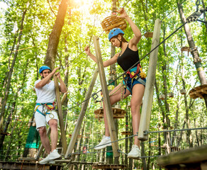 Young couple having fun time in adventure rope park.