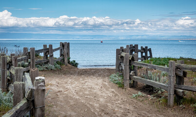 A sandy path lined by wooden fence leads to Del Monte Beach, along the central California Pacific...