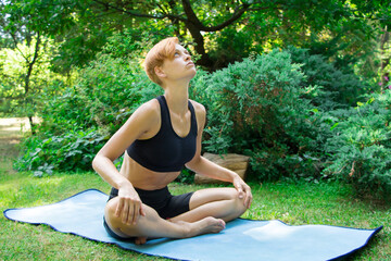 woman doing yoga in the park, young girl doing various wellness exercises, the concept of a healthy lifestyle and health care and her body