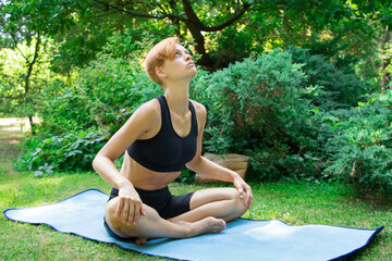 woman doing yoga in the park, young girl doing various wellness exercises, the concept of a healthy...