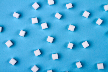 Sugar cubes on blue background. Granulated sugar is unhealthy food.