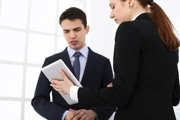 Businessman and woman using tablet computer for discussing questions in office. Partners or colleagues at meeting. Business cooperation concept