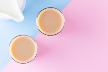 Obraz na płótnie Canvas Milk tea on a pink-blue background. Turkish tea cups and milk jug. Cup of traditional English black tea with milk. Copy space. Top view